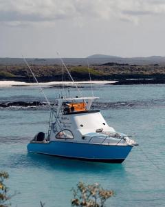 a blue and white boat in the water at San Cristóbal Surf House lll in Puerto Baquerizo Moreno