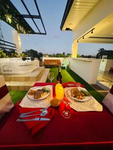 a table with two plates of food and a bottle of wine at The Penthouse With Outdoor Jacuzzi Private Rooftop Solar Powered Energy in Puerto Princesa City
