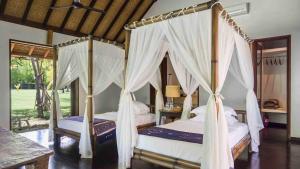 a bedroom with two beds with drapes at Luxury Beachfront Villa in North Lombok in Gili Islands +46 photos