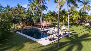 an aerial view of a resort swimming pool with palm trees at Luxury Beachfront Villa in North Lombok in Gili Islands