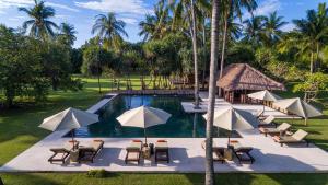 an outdoor pool with chairs and umbrellas at Luxury Beachfront Villa in North Lombok in Gili Islands