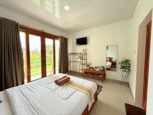 a bedroom with a bed and a large window at The Angga House in Bangli