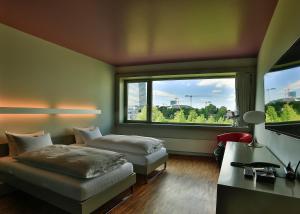 una camera d'albergo con due letti e una grande finestra di Dasbreitehotel am Rhein a Basilea