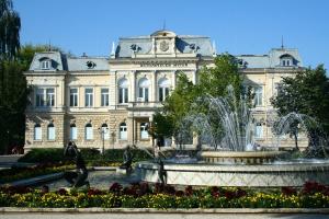 a large building with a fountain in front of it at Old Center Apartment in Ruse