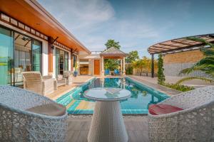 a pool with chairs and a table next to a house at Rawayana Villas in Rawai Beach