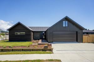 a black house with a garage at Rua Street Escape in Wanaka