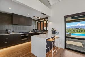 a kitchen with a counter and a pool in the background at Wanaka Mountain Oasis - Spa & Pool in Wanaka