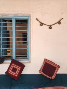a wall with two pillows and a window and a clock at Peshagar Guest House in Hampi