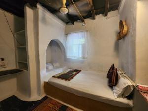a small room with a bed and a window at Peshagar Guest House in Hampi