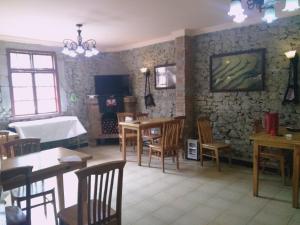 Jacky's Guesthouse في يوانيانغ: غرفة طعام بها طاولات وكراسي وجدار حجري