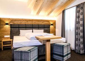 1 dormitorio con 1 cama con mesa y 2 taburetes en Hotel Garni Persutt, en Ischgl