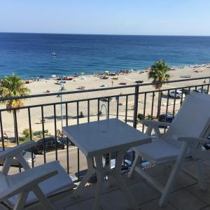 a table and chairs on a balcony with a beach at Sharm 2 in Marina di Gioiosa Ionica