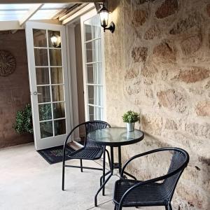 a table and chairs on a patio with a stone wall at Hahndorf Oak Tree Cottages in Hahndorf