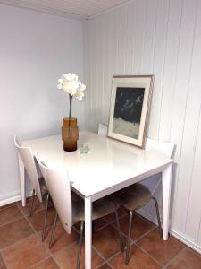 a white table and chairs with a vase of flowers on it at Cozy apartment in Drammen +3 photos
