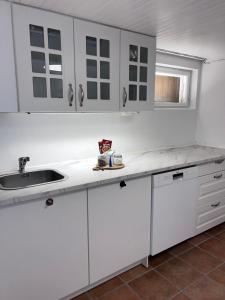 a kitchen with white cabinets and a sink at Cozy apartment in Drammen