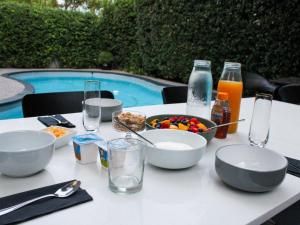 a table with a bowl of food and drinks next to a pool at Oak Manor Boutique Guest House in Cape Town