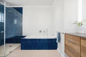 a bathroom with a tub and a shower with blue tiles at Sugarbird in Velddrif +49 photos