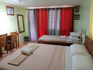 a bedroom with two beds and red curtains at Island - Escape Homestay in Burgos