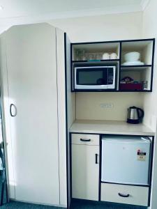 a kitchen with a microwave and a refrigerator at Legends Motel in Palmerston North