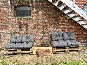 two chairs sitting on pallets next to a brick wall at Le Cosy Duplex in Amay