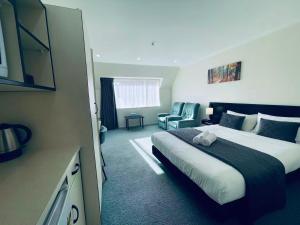 a hotel room with a bed and a chair at Legends Motel in Palmerston North