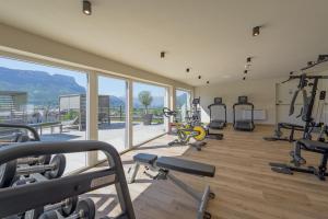 Ein Fitnessstudio mit mehreren Ergometern in einem Raum mit Fenstern in der Unterkunft Hotel Cornelian Suites & Rooms in Appiano sulla Strada del Vino