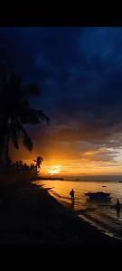 a sunset on a beach with a boat in the water at Stanley House Seaview Apartments in Panglao Island