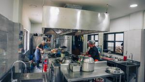 two men in a kitchen preparing food in a kitchen at White Leaf Resort - Green River View Resort in Dolālghāt