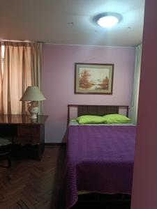 a bedroom with a purple bed with a lamp and a table at Casa Junto al Rio in Arequipa
