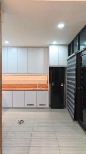 a kitchen with white cabinets and a black refrigerator at Hotel The Island in Pangkor