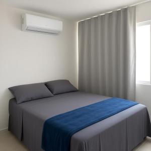 a bedroom with a bed with blue sheets and a window at Casa condominio Carpe Diem in Marechal Deodoro