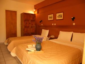 um quarto de hotel com duas camas e um vaso de flores em Ξενοδοχείο Αφροδίτη- Hotel Aphrodite em Lepanto