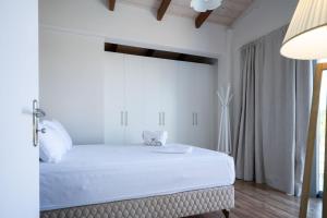 a white bedroom with a large bed and a lamp at Le petit luxury apartment in Preveza +26 photos