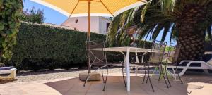 a table and chair with an umbrella on a patio at Maison du Palmier in La Brée-les-Bains