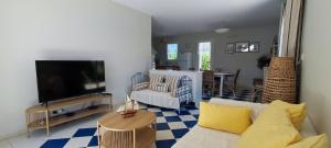 a living room with a couch and a flat screen tv at Maison du Palmier in La Brée-les-Bains