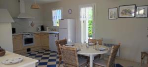 a kitchen with a table with chairs and a refrigerator at Maison du Palmier in La Brée-les-Bains