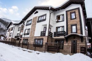 una casa en la nieve con una valla en Apartments Chudo, en Estosadok