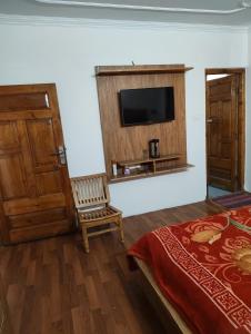 a bedroom with a bed and a tv on a wall at Hotel Premier in Manāli