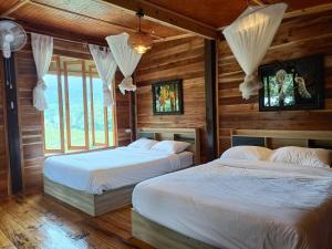 two beds in a room with wooden walls and windows at Motho Homestay โมโทโฮมสเตย์ in Chom Thong