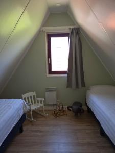 a attic room with two beds and a window at Groene Specht 16 in Gramsbergen +23 photos