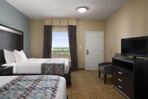 a hotel room with two beds and a flat screen tv at Days Inn & Suites by Wyndham Gonzales TX in Gonzales