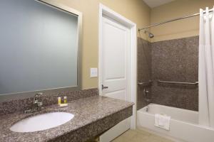 a bathroom with a sink and a bath tub at Days Inn & Suites by Wyndham Gonzales TX in Gonzales