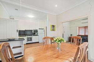 a kitchen and dining room with a wooden table and chairs at Red Brick Beauty - Central Cottage in Albury +7 photos