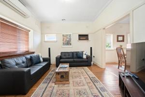 a living room with a black couch and a table at Red Brick Beauty - Central Cottage in Albury
