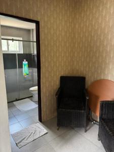 a bathroom with a toilet and a chair and a mirror at Lakambini Transient in El Nido
