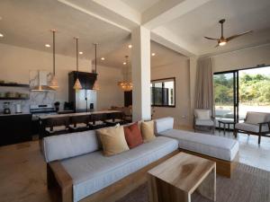 a living room with a white couch and a kitchen at Casa Sur – Oceanfront Villa in Placencia