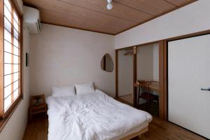 ein Schlafzimmer mit einem weißen Bett und einem Tisch in der Unterkunft Hagi micro hotel in Gero