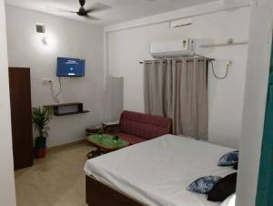 a room with a bed and a couch and a tv at Hotel Vasu in Gopālganj
