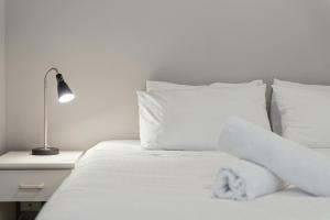 a white bed with white pillows and a lamp on a night stand at Horizons 302 in Jindabyne