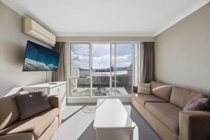 a living room with a couch and a tv at Horizons 302 in Jindabyne